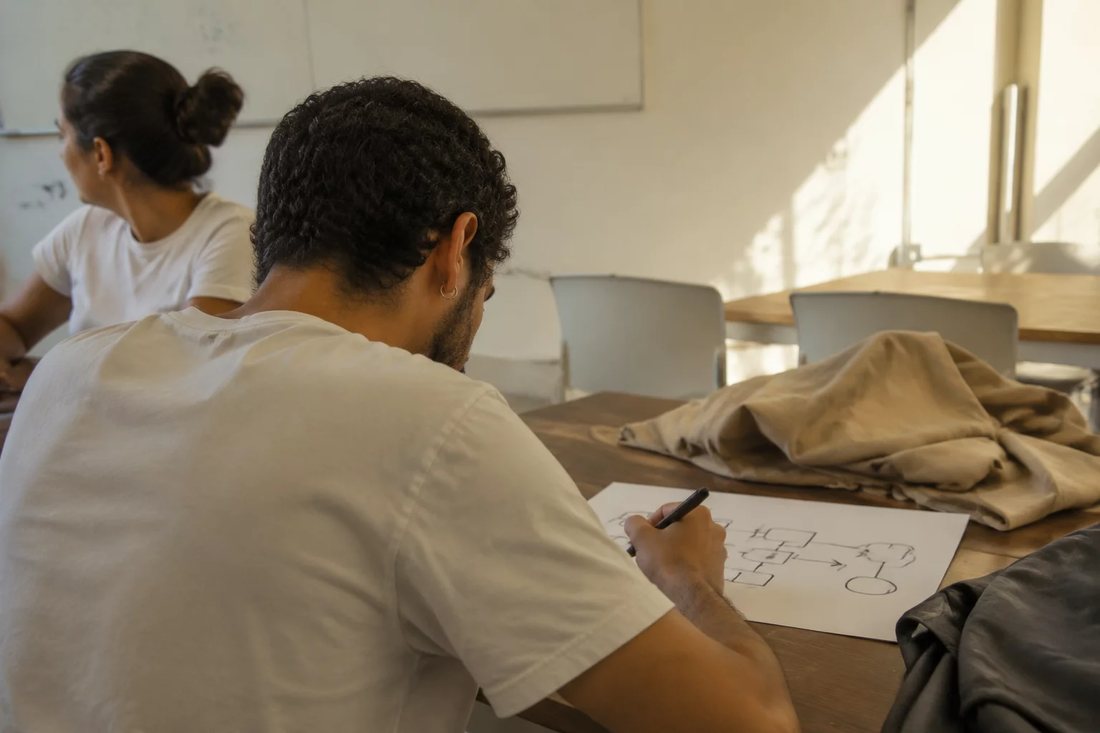 Duas pessoas relendo anotações no tablet apoiado na mesa de madeira